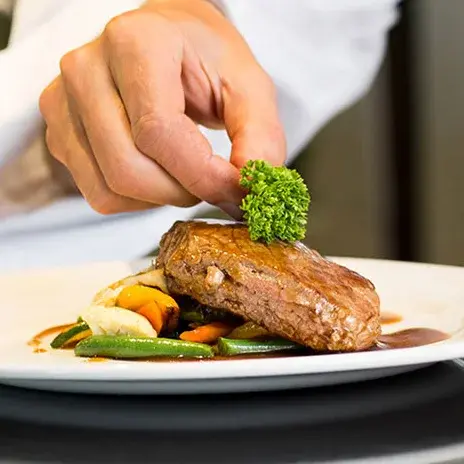 Maple Ridge Chef Created Meals, chef garnishing a plate.